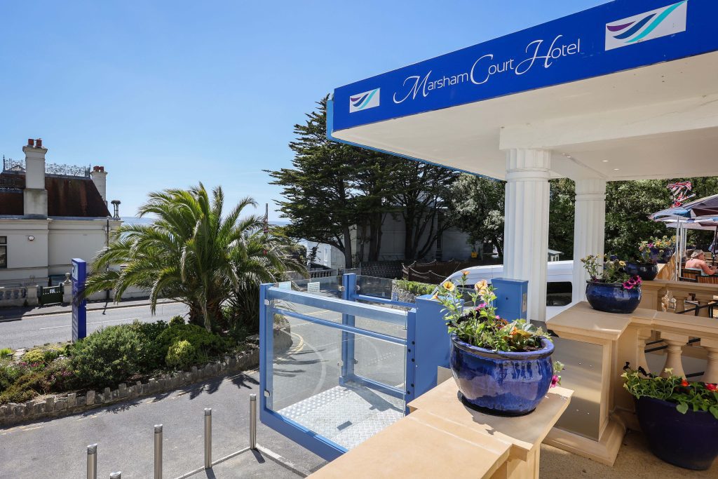 An image showing the entrance of the Marsham Court Hotel with a wheelchair lift and sea view in the distance.