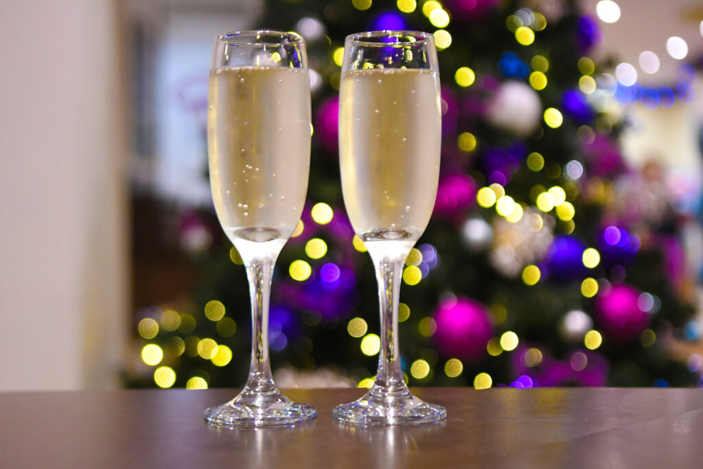 2 glasses of Champagne in front of a brightly lit Christmas Tree
